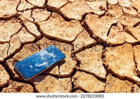 a broken smartphone lies on dry soil in the desert. the concept of all that remains after people is dry land and smartphones.