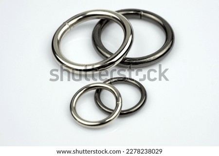 Large and small metal rings on a white background. Metallic black and gray chrome rings for making bags and backpacks. High quality sewing accessories.