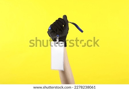 Female hand in working fabric glove holding Identification white blank id cards on yellow background