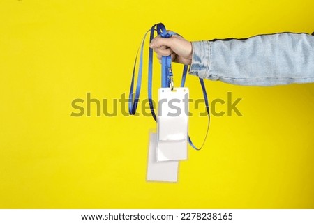 Hand holding Identification white blank id cards on yellow background