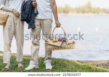 Couple walking in garden with picnic basket. in love couple is enjoying picnic time in park outdoor