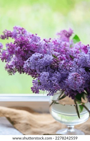 bouquet of purple blooming lilacs in a vase on the window