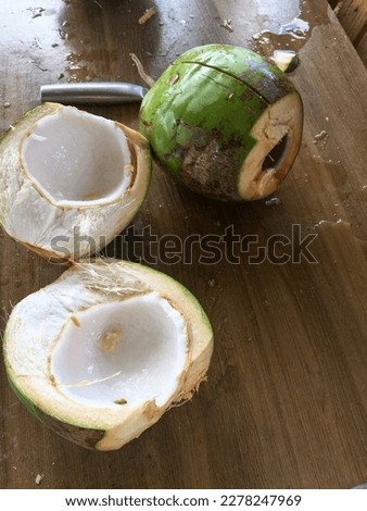 Fresh coconut fruit ready to serve as a drink. Young open cut coconut fruit to drink sweet juice and eat. Wooden background.