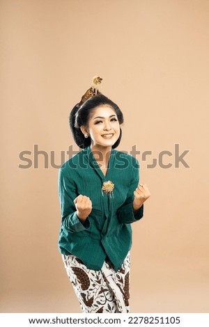 happy asian woman in green kebaya bending and clenching her arms on isolated background