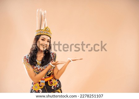 asian woman in king bibinge standing with smile and pointing on empty space at her left side on isolated background