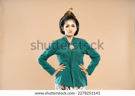 javanese woman in green kebaya standing with sullen face and put her hands on her waist on isolated background
