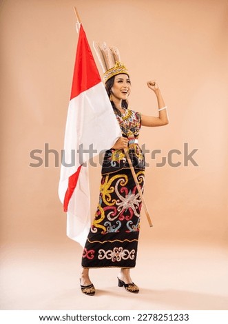 asian woman in king bibinge screaming and clenched her arm while holding the indonesian flag on isolated background