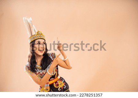 happy asian woman in traditional clothes of dayak tribe looking and pointing up on isolated background