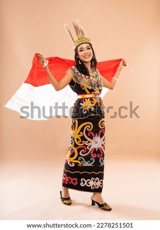 asian woman in king bibinge standing and waving the indonesian flag behind her body on isolated background