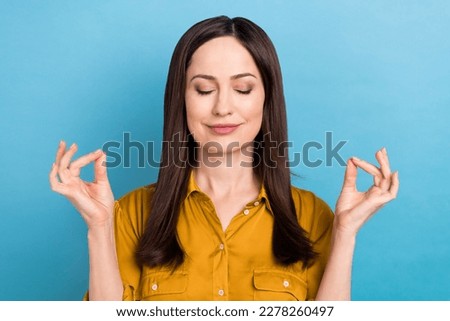 Photo of adorable dreamy woman wear yellow shirt smiling closed eyes enjoying yoga isolated blue color background