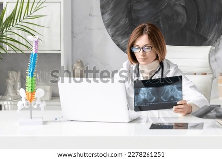 Young female doctor orthopedist sits at the desk and works in her office in the modern hospital