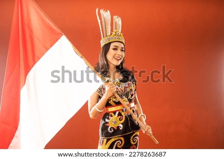 asian woman in king bibinge smiling showing her teeth while holding the indonesian flag on isolated background