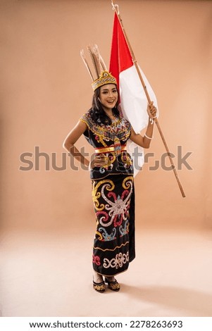 asian woman in king bibinge put her hand on her waist and raising indonesian flag on isolated background