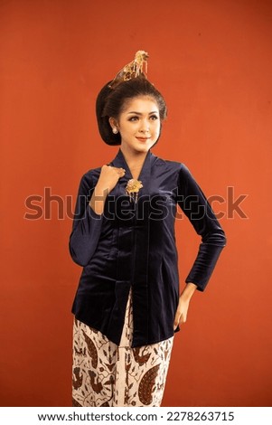 asian woman in navy kebaya standing with smile and put her hand on her waist on isolted background