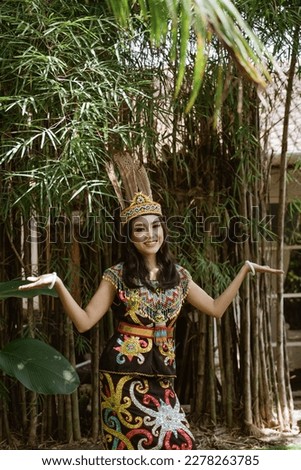 asian woman in king bibinge standing raising her hands with the bamboo at the background