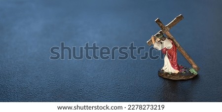 Statue of Jesus Christ carrying his cross on Calvary on dark abstract background. Biblical scene of Passion of the Christ on Good Friday. Symbol of Lent, Faith in God, Church. banner. copy space