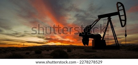 Silhouette of oil pump in desert landscape at sunset. Space for text and or images. 
