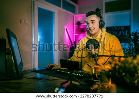 Young man play video games on pc computer while streaming to social media or internet online playtrough or walktrough video male gamer having fun at home wear headphone copy space