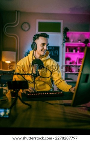 Young man play video games on pc computer while streaming to social media or internet online playtrough or walktrough video male gamer having fun at home wear headphone copy space Royalty-Free Stock Photo #2278287797