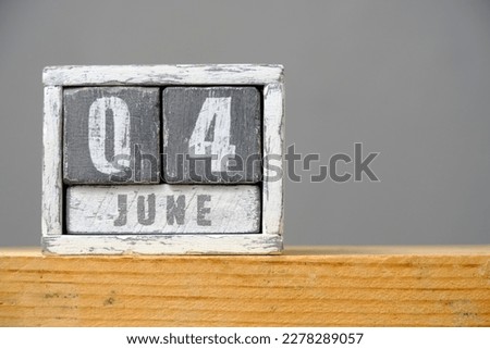 Calendar for June 04 made of wooden cubes standing on shelf on gray background.With an empty space for your text