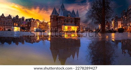 Amsterdam City Night Skyline Panorama near Nieuwmarkt after March rain in Netherlands, dramatic cloudscape and water reflections of the plaza buildings and traditional Dutch houses