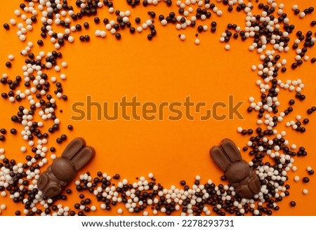 easter bunnies around chocolate balls on an orange background