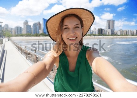 Beautiful girl takes selfie picture with modern skyscrapers skyline on the ocean
