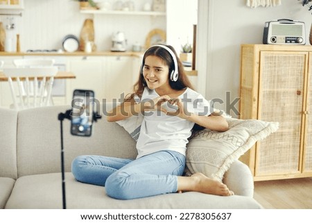 Preteen 12s girl blogger record video for vlog, showing heart sign, make call, lead stream with friends use modern tech. Streamer activity, igeneration, fun and home use internet, screen camera view.  Royalty-Free Stock Photo #2278305637