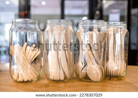 Wooden cutlery (knives, forks, spoons, teaspoons) in glass jars on wooden bench. No more single-use plastic cutlery. Royalty-Free Stock Photo #2278307029