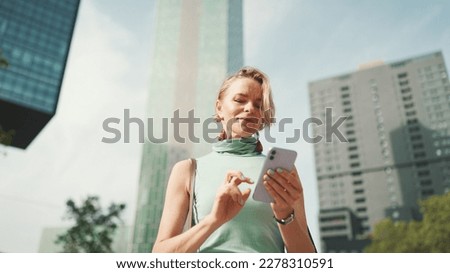 Friendly woman with short blonde hair in casual clothes looking at map trying to find his way using his mobile phone. Woman using map app in cellphone outdoors Royalty-Free Stock Photo #2278310591