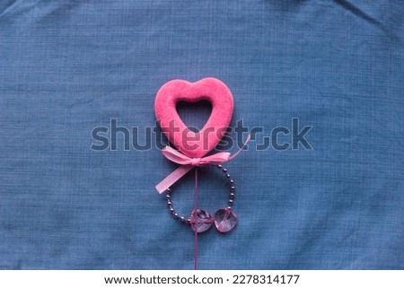 velvet pink heart with a bow on the background of blue denim fabric