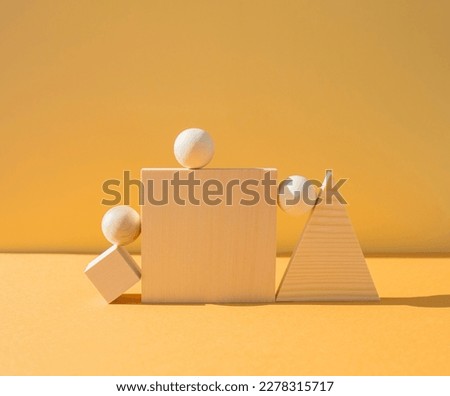 Several wooden figures arranged on yellow background, hard light. Balance concept.