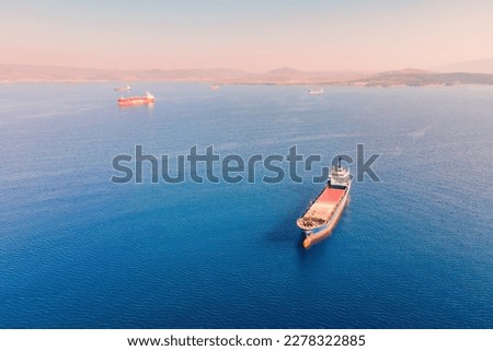 General cargo vessel or bulk carrier anchored at sea nearby port awaiting loading, Aerial establishing shot