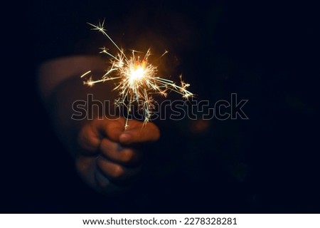 Woman hand holding a burning sparkler. Christmas and new year sparkler holiday background