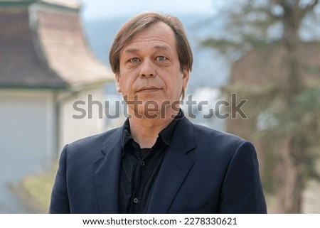 Street portrait of a man 40-50 years old in a black suit on a neutral blurred background. Perhaps he is just a buyer, an actor, a military pensioner, a company manager, lives outside the city. Royalty-Free Stock Photo #2278330621