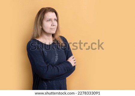 A woman on a yellow background looks up with hope, there are difficulties and problems in her life, but she is not disappointed, she believes and prays, she wants to be a good mother and wife Royalty-Free Stock Photo #2278333091