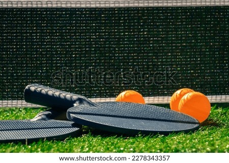 ping pong paddles with orange balls on grass