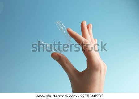 Aligners for aligning teeth on a blue background in a female hand Royalty-Free Stock Photo #2278348983