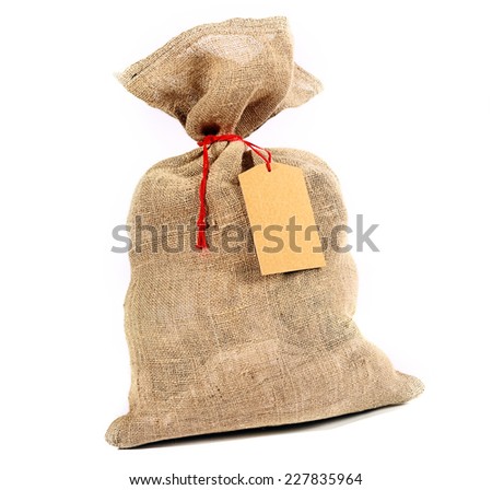 Rustic burlap sack tied with red string with a blank gift tag for your Christmas or seasonal greeting over white