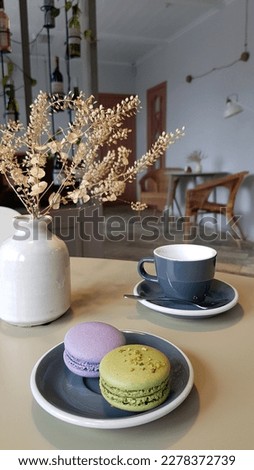 French dessert sweets, colored macaroons arranged on a saucer with a cup on the table, vintage look in pastel colors