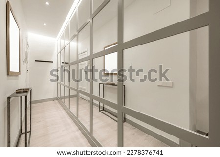 Narrow hallway in a home with an industrial-style appliance and a wall covered in gray-edged mirrors Royalty-Free Stock Photo #2278376741