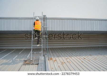 Man worker wearing white hardhat and protectibe vest climbing the ladder.
