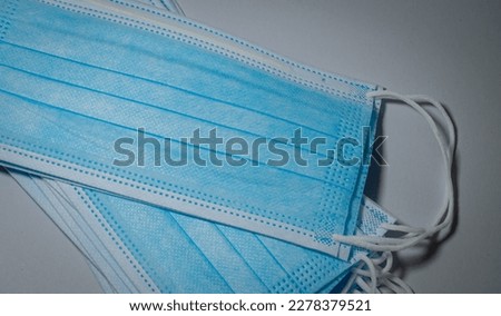 Blue surgical masks in close up shot stacked in layers on gray background, Bacteria protection concept.
