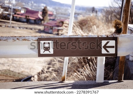 The sign indicating the way to the train on the railing on the side of the road.