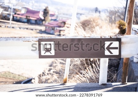 The sign indicating the way to the train on the railing on the side of the road.