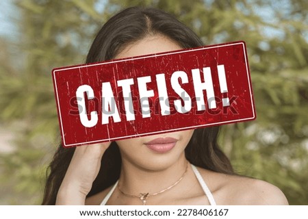 A catfish alert sign or someone pretending to be an attractive person. A fake profile using a stolen photo. A false identity used to pursue deceptive online romance. Catfishing detection concept. Royalty-Free Stock Photo #2278406167