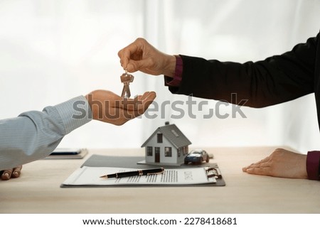 Businessman, insurance sales agent handing over house and car keys to customer in trading or renting in mutual agreement at security concept office housing investment. Royalty-Free Stock Photo #2278418681