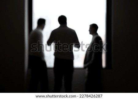 silhouette of a business man standing in the morning talking in a dark room on a high rise in the city