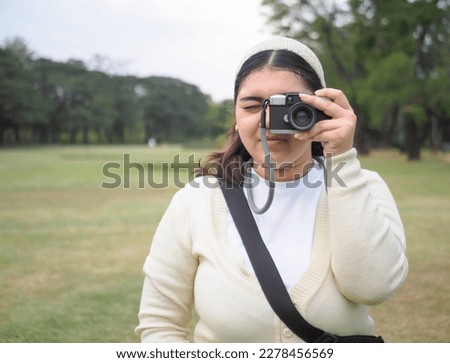 portrait young woman asian chubby cute beautiful one person wear black shirt look hand holding using camera in garden park outdoor evening sunset time smiling cheerful happy relax summer day