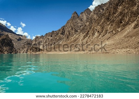 Beautiful view of an aqua colored Lake in Pakistan with mountains and clear sky in background